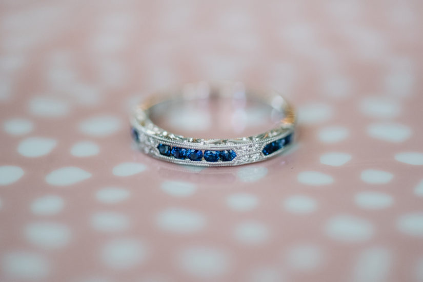 Wedding band with blue colored sapphires in white gold on a pink polkadot background