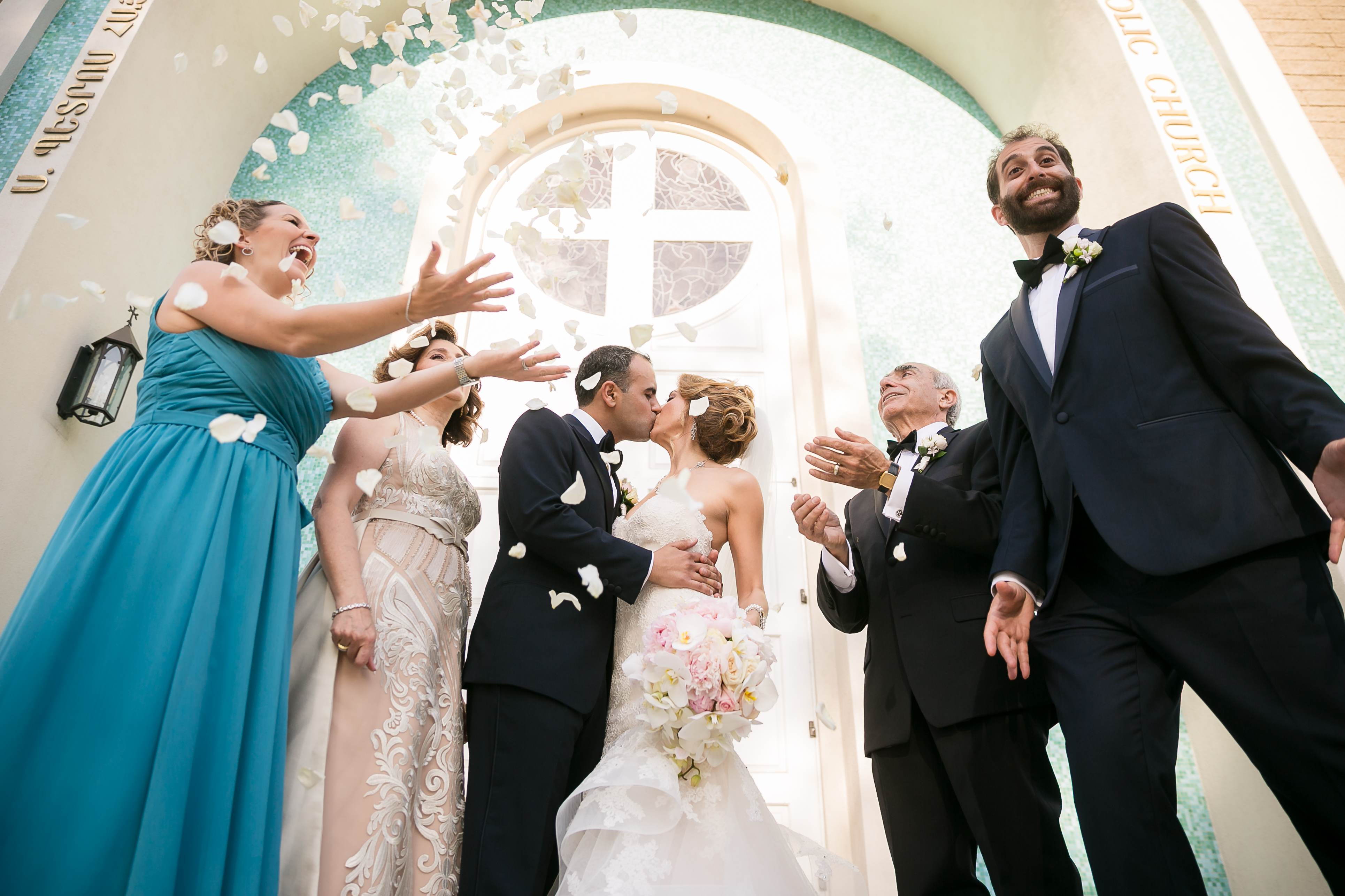 Throwing flower petals in the air while the bride and groom kiss during their wedding