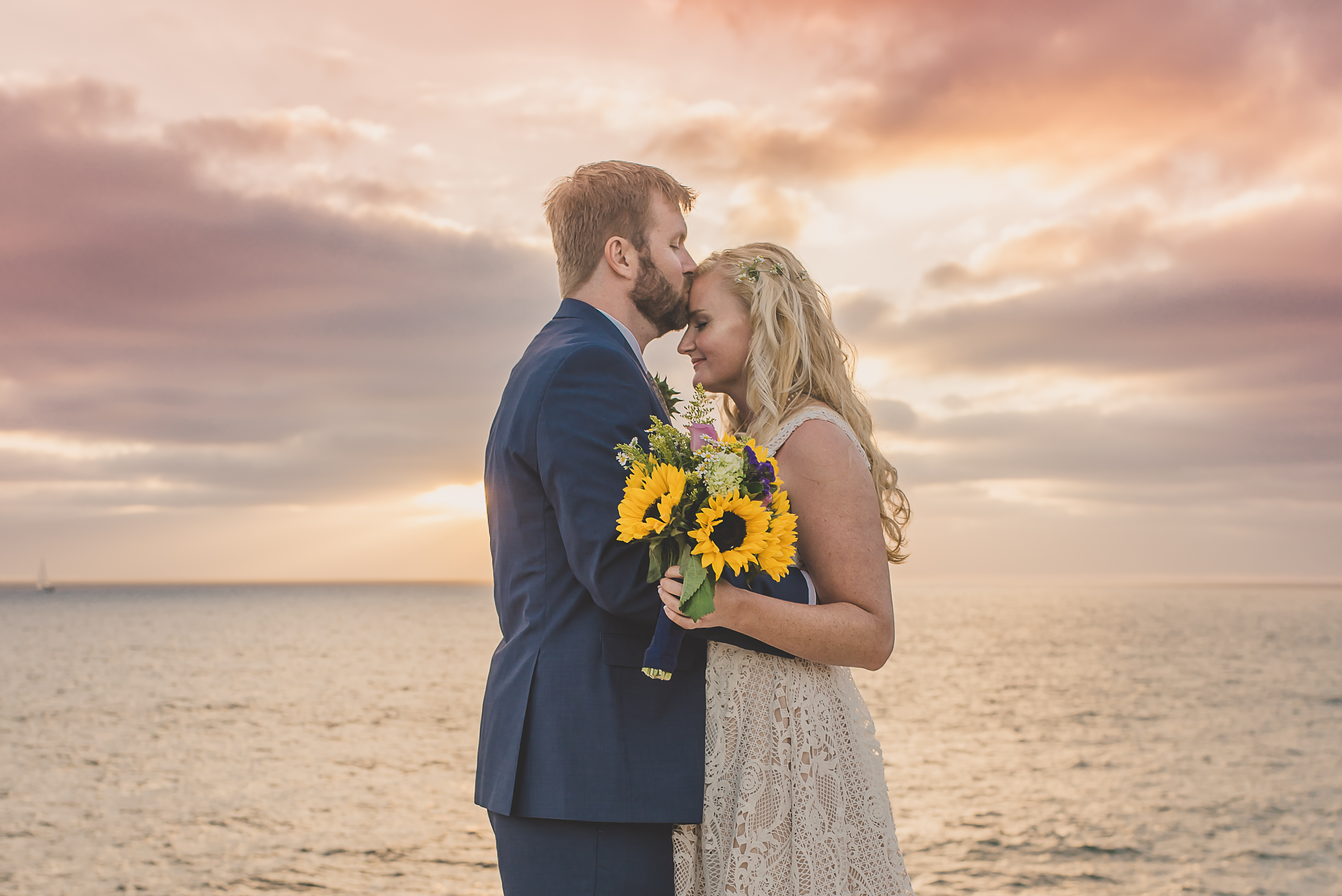 Couple kissing during wedding photoshoot during sunset with sunflowers and Kirk Kara rings