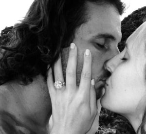 Couple kissing with custom white gold engagement ring.