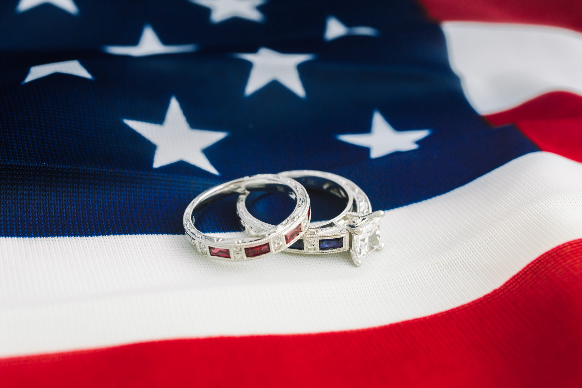 White gold engagement ring with sapphires and diamonds with white gold wedding band with rubies on American flag