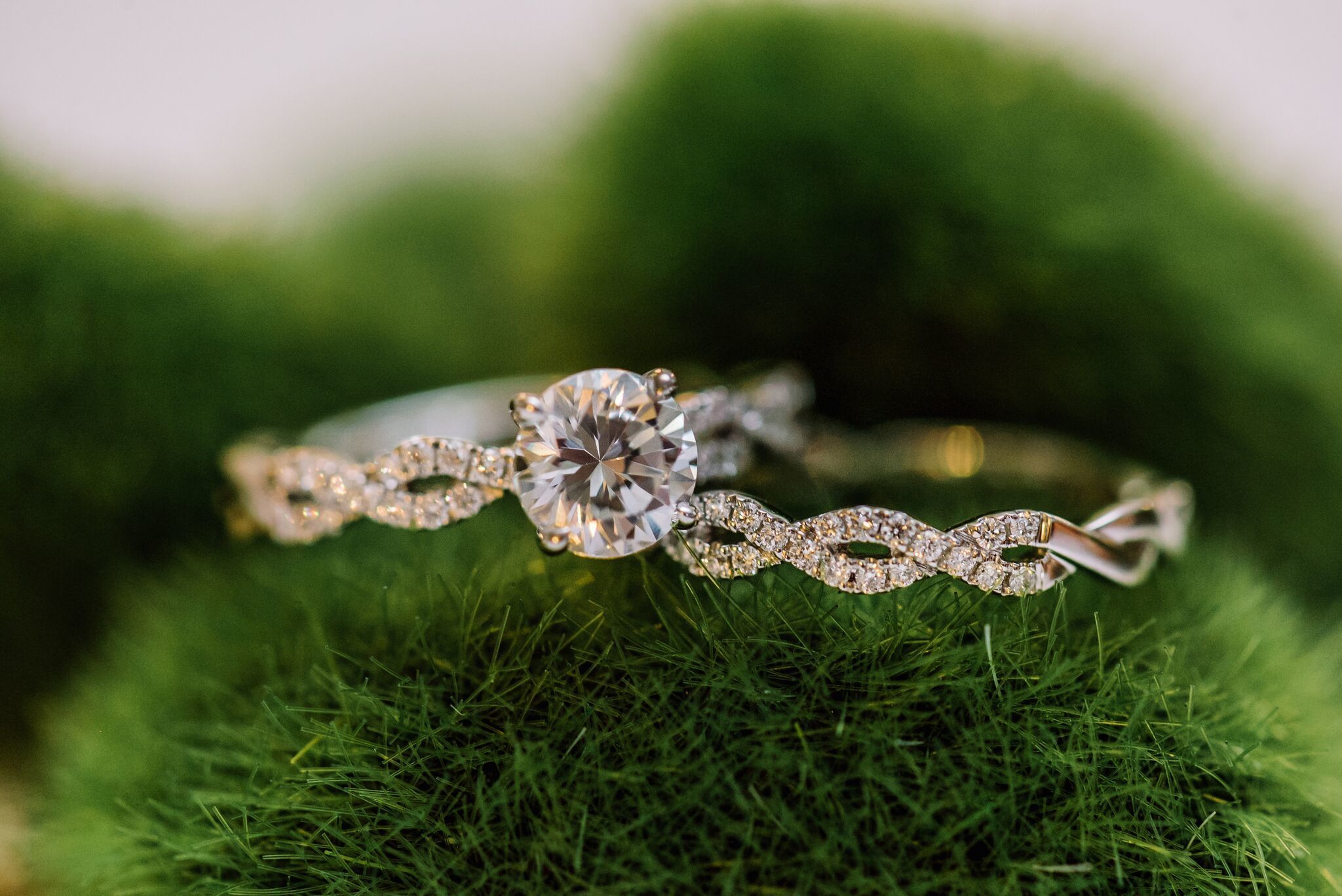 Matching diamond and white gold engagement and wedding ring set on green moss