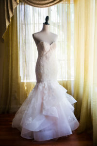 Wedding dress on a stand with golden curtains in the background 