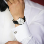 Man adjusting cufflinks while getting ready for a wedding wearing a fine watch and a white shirt