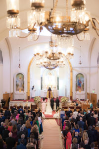 Looking down the isle of a traditional Armenian wedding ceremony with chandeliers hanging overhead