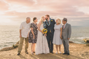 Sun setting on the beach in Hawaii with bride and groom and family