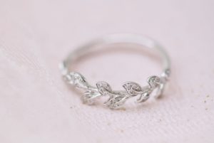 White gold engagement ring with leaves on a pink background