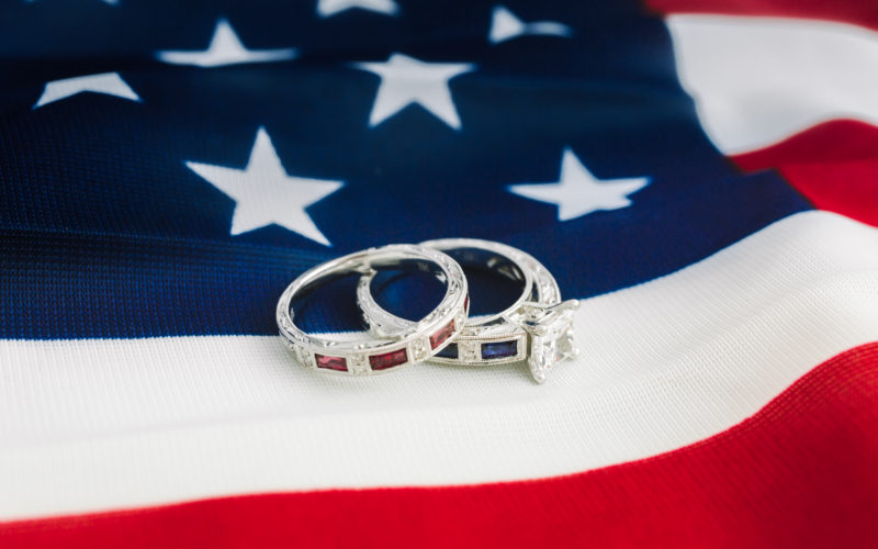 White gold engagement ring with sapphires and diamonds with white gold wedding band with rubies on American flag